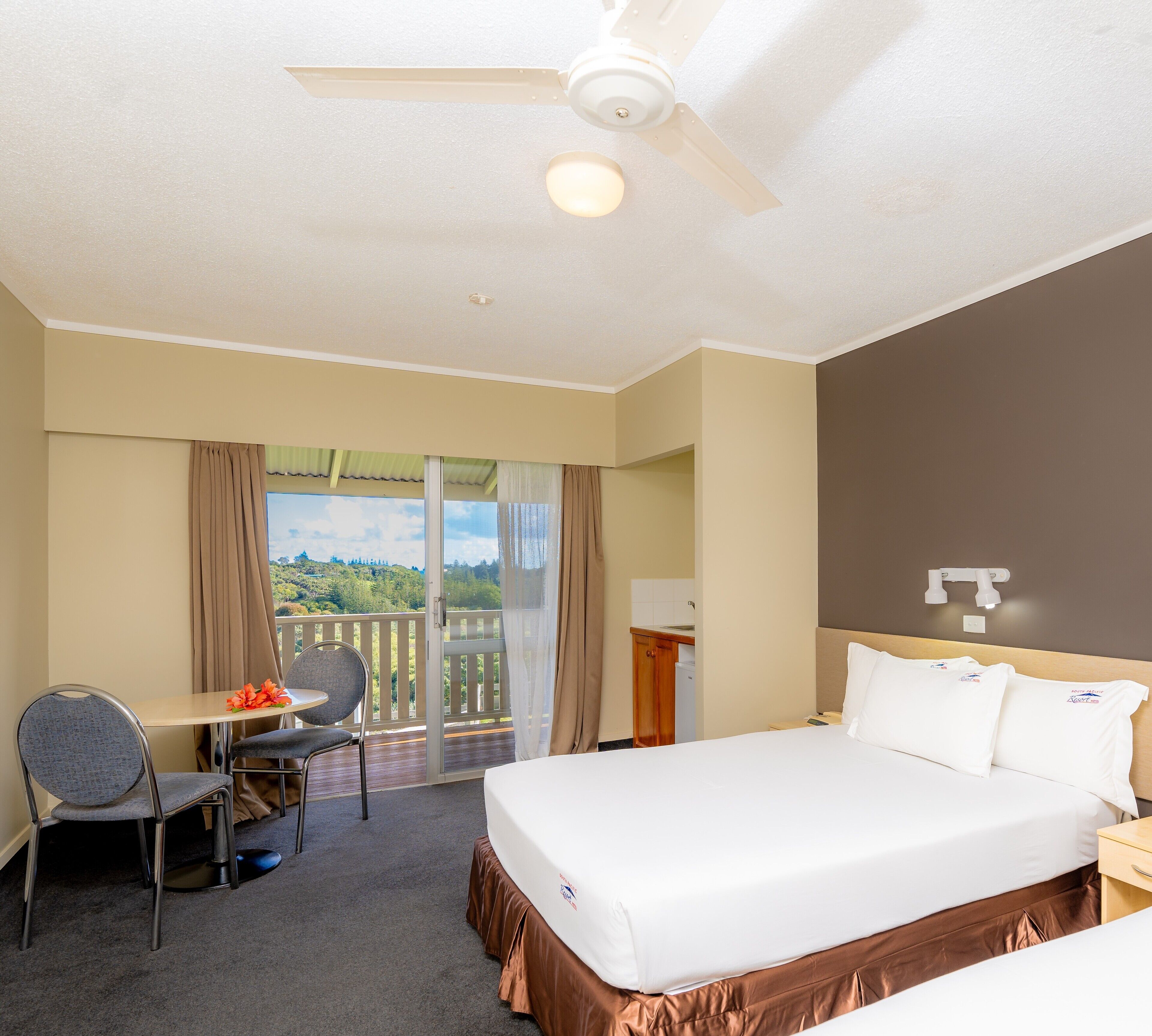 Ein Hotelzimmer mit Bett, Schreibtisch, Stuhl und einem Balkon mit Blick.
