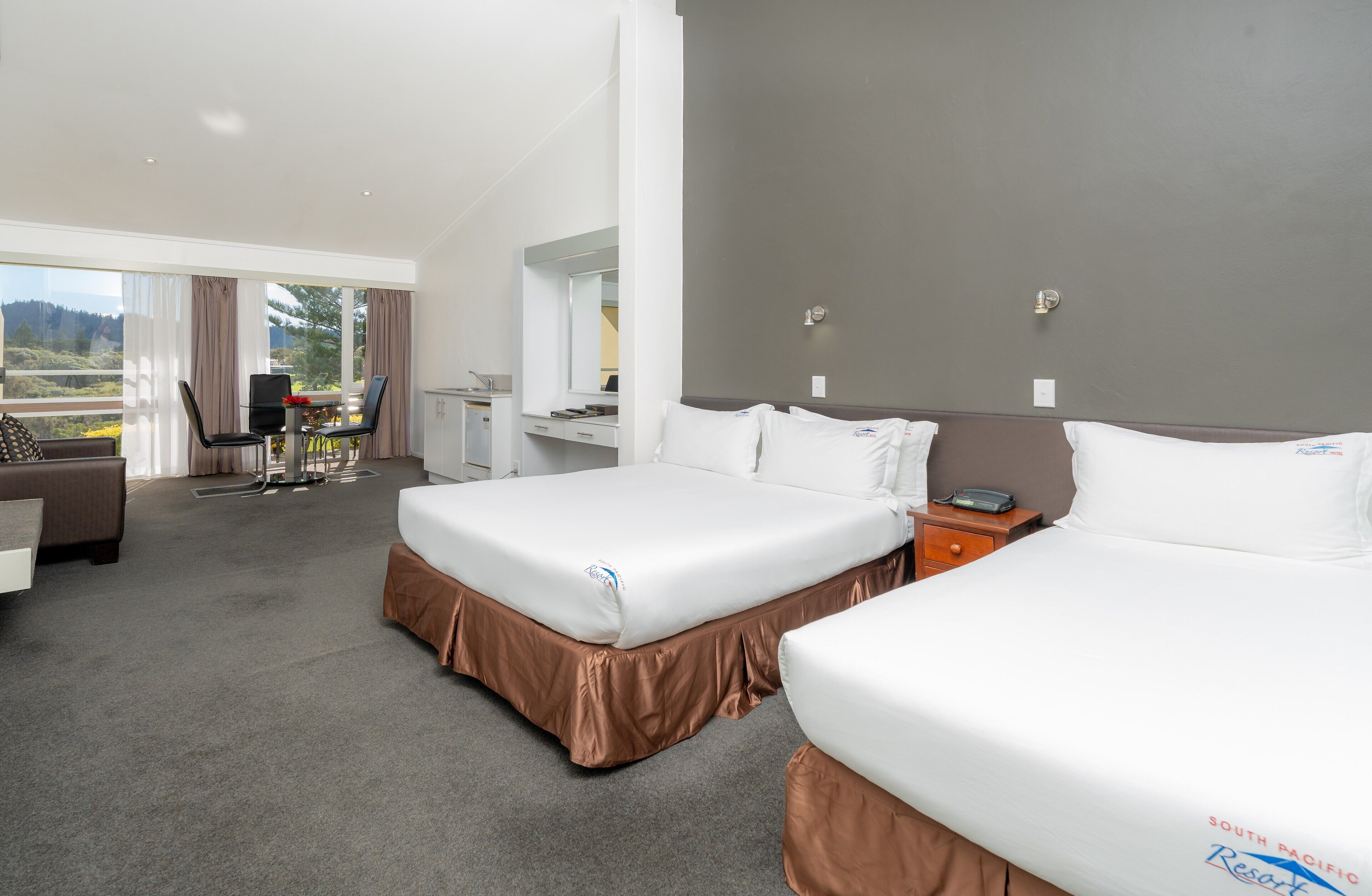 A hotel room with two beds, a desk, and a chair.