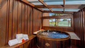 Ein hölzerner Spa-Bereich mit Whirlpool, Holzbänken und Blick auf einen Golfplatz.