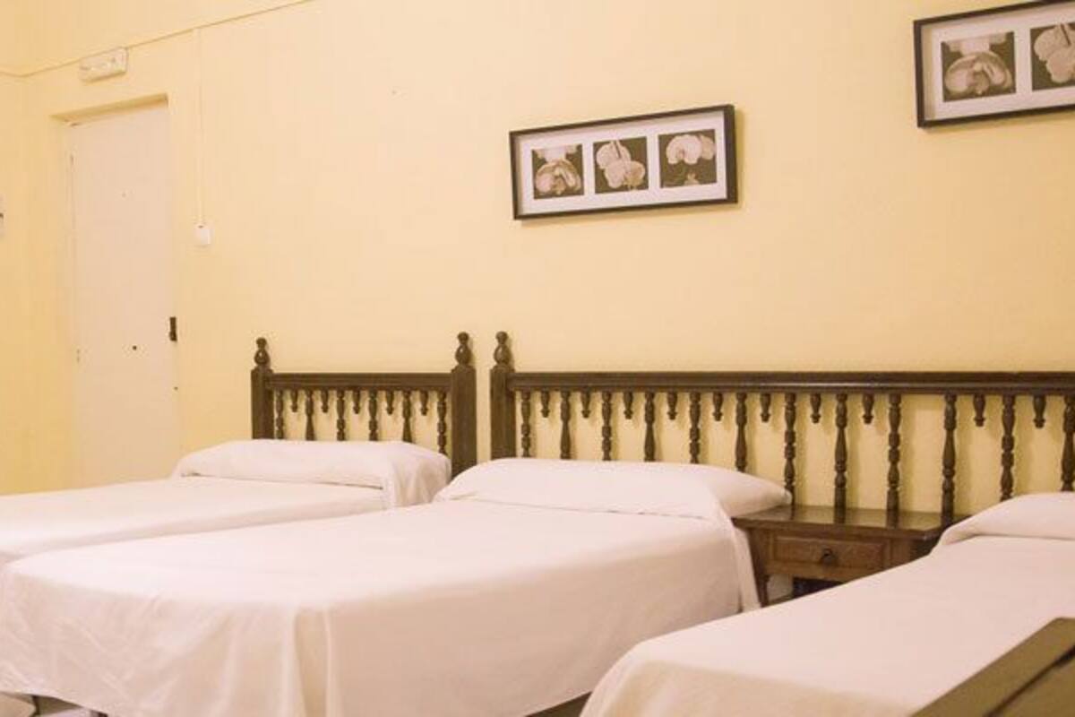 A room with two single beds, a wooden headboard, a wardrobe, and a wall-mounted picture.