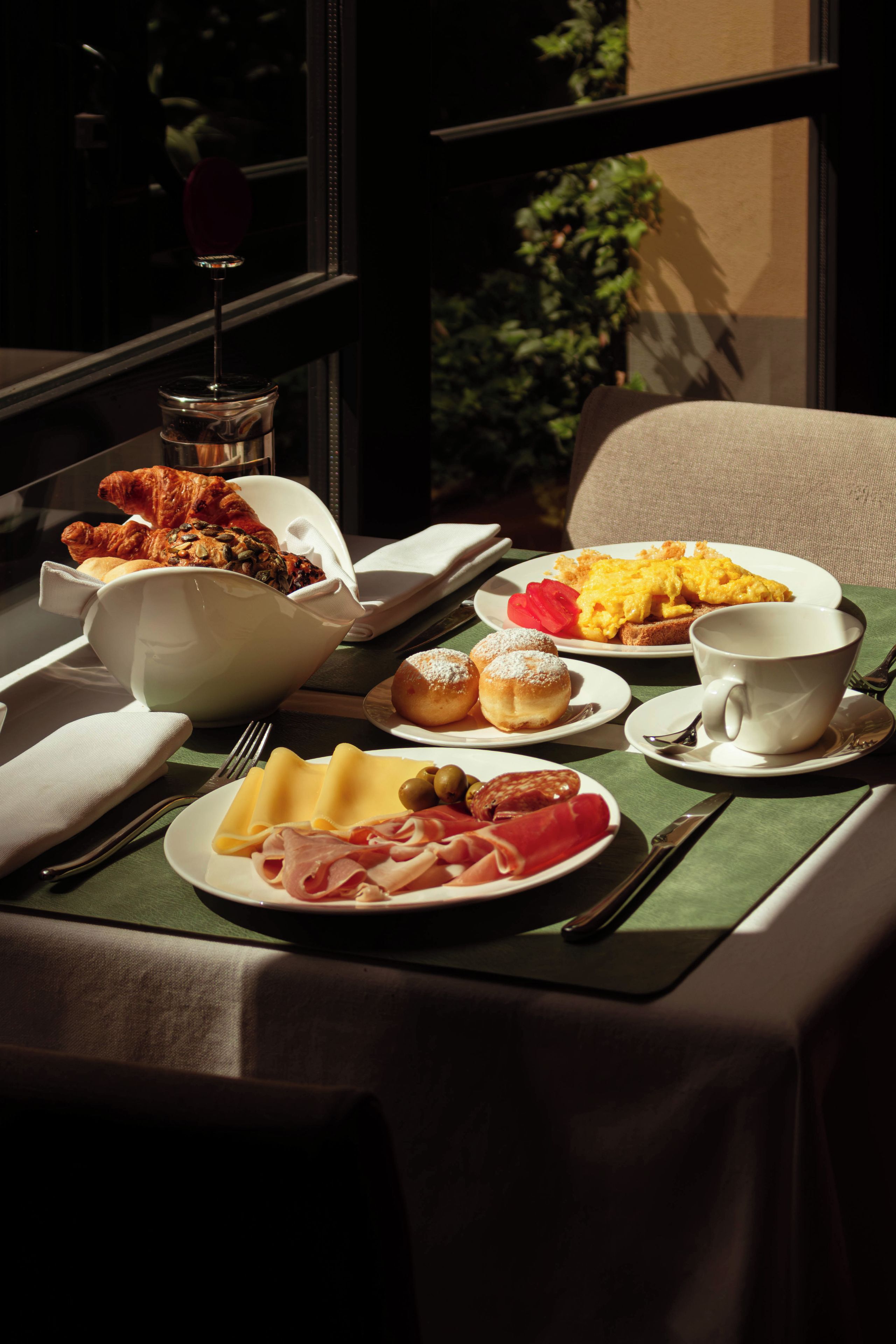 A breakfast table with plates of food, a cup, and cutlery.