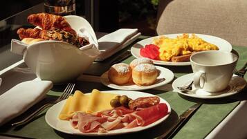 A breakfast table with plates of food, a cup, and cutlery.