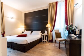 Une chambre d’hôtel comprenant un lit, des tables de chevet, un bureau, une chaise et une machine à café.