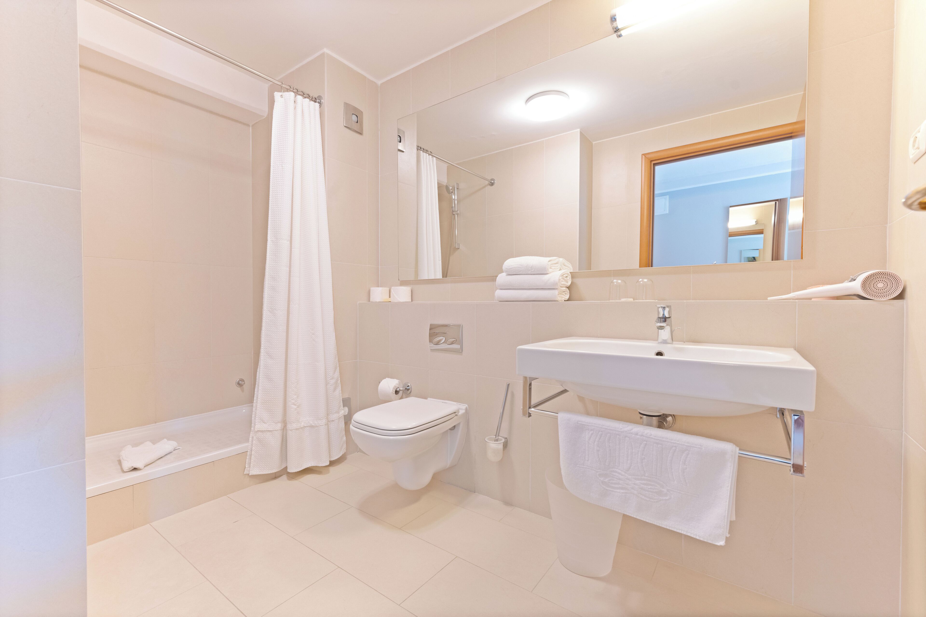 A modern bathroom with a bathtub, toilet, sink, and a large mirror.