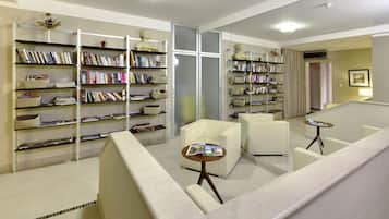 A modern library with multiple bookshelves, comfortable seating, and a large mirror.