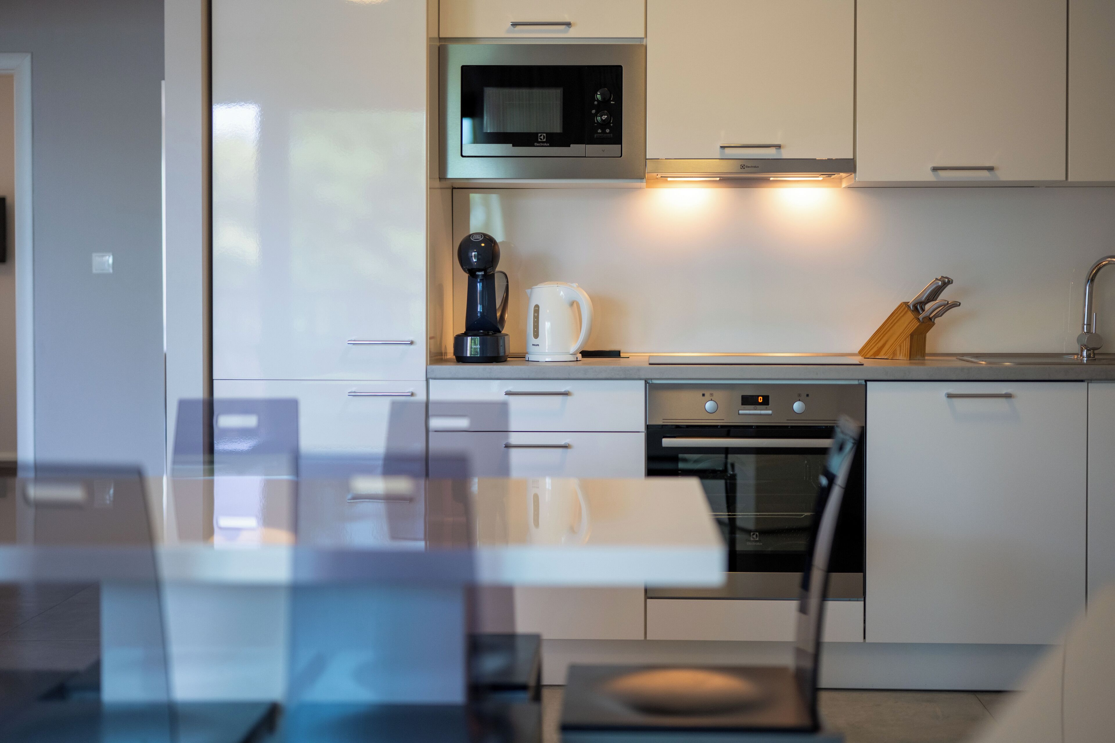A modern kitchen with white cabinets, a microwave, a coffee maker, and a dishwasher.