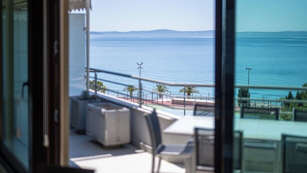 Ein Balkon mit Meerblick, Gartenmöbel und Geländer.