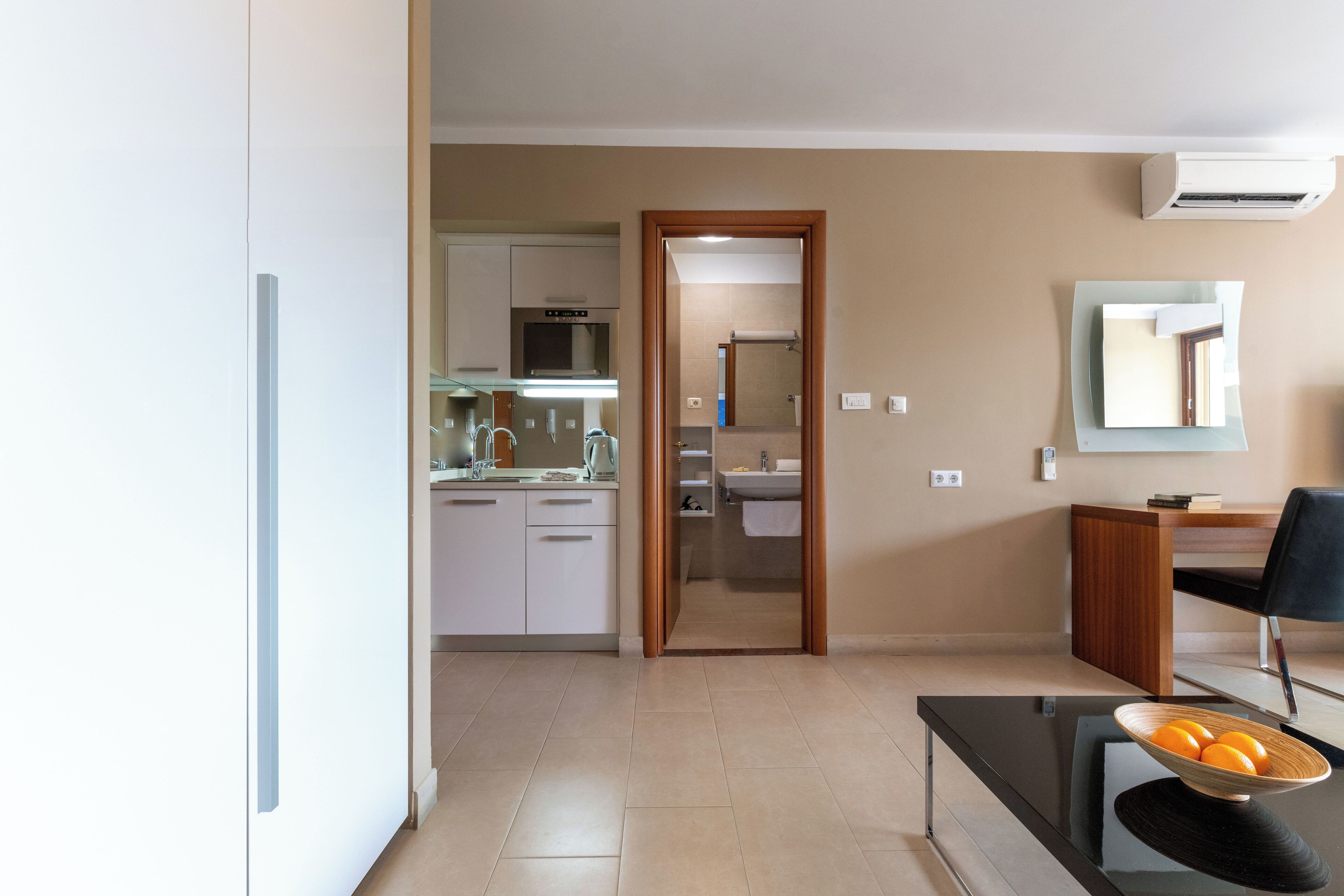 Una sala de estar moderna con comedor, una cocina al fondo y un baño visible a través de una puerta abierta.