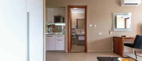 A modern living room with a dining area, a kitchen in the background, and a bathroom visible through an open door.