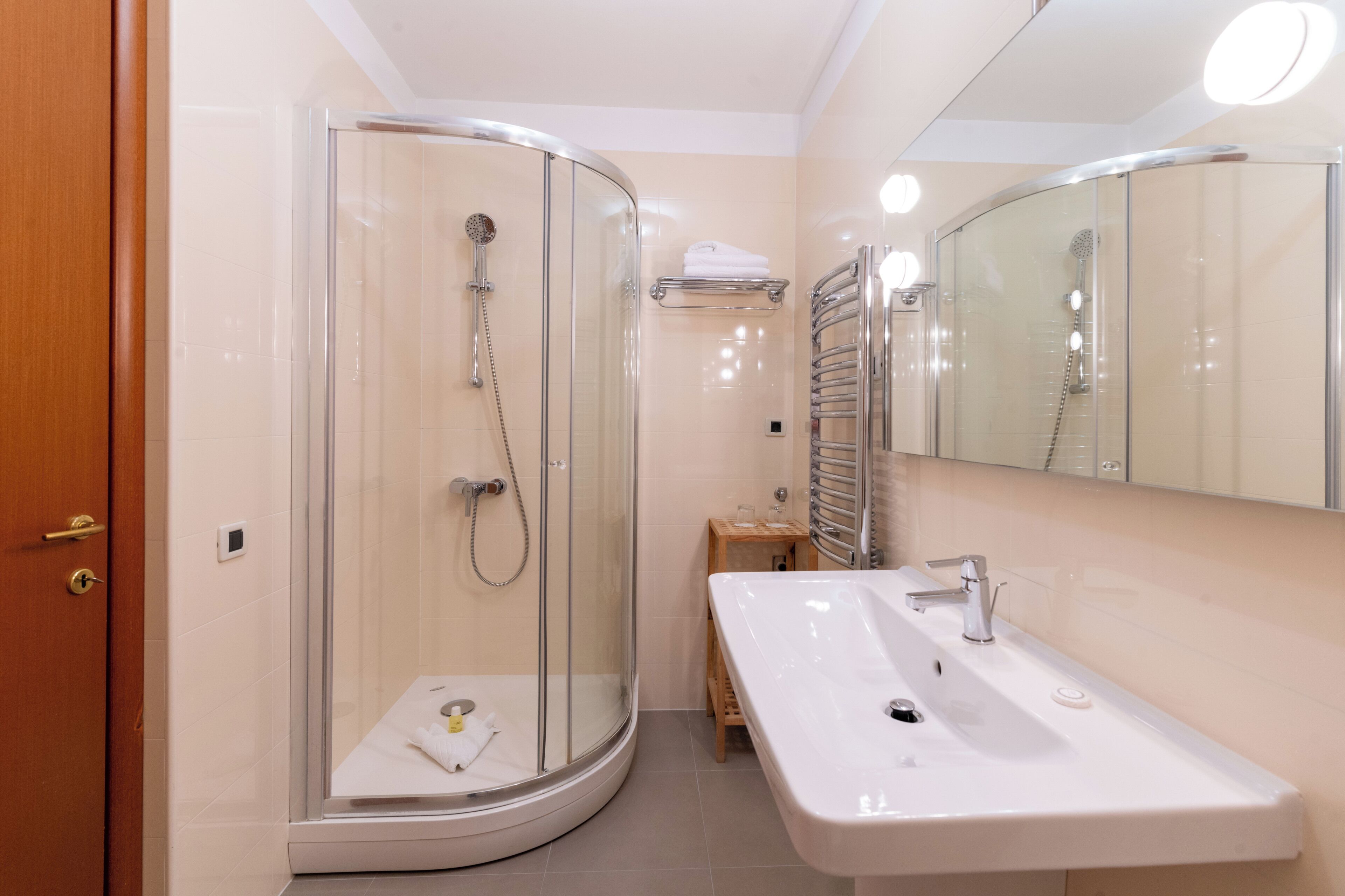 Une salle de bain moderne avec une douche à parois de verre, un lavabo blanc et un miroir au-dessus du lavabo.