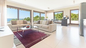 Ein modernes Wohnzimmer mit Sofa, Couchtisch und Meerblick.
