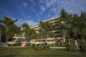 A multi-story building with a flat roof, surrounded by trees and a grassy area. - The Residence (Podstrana)