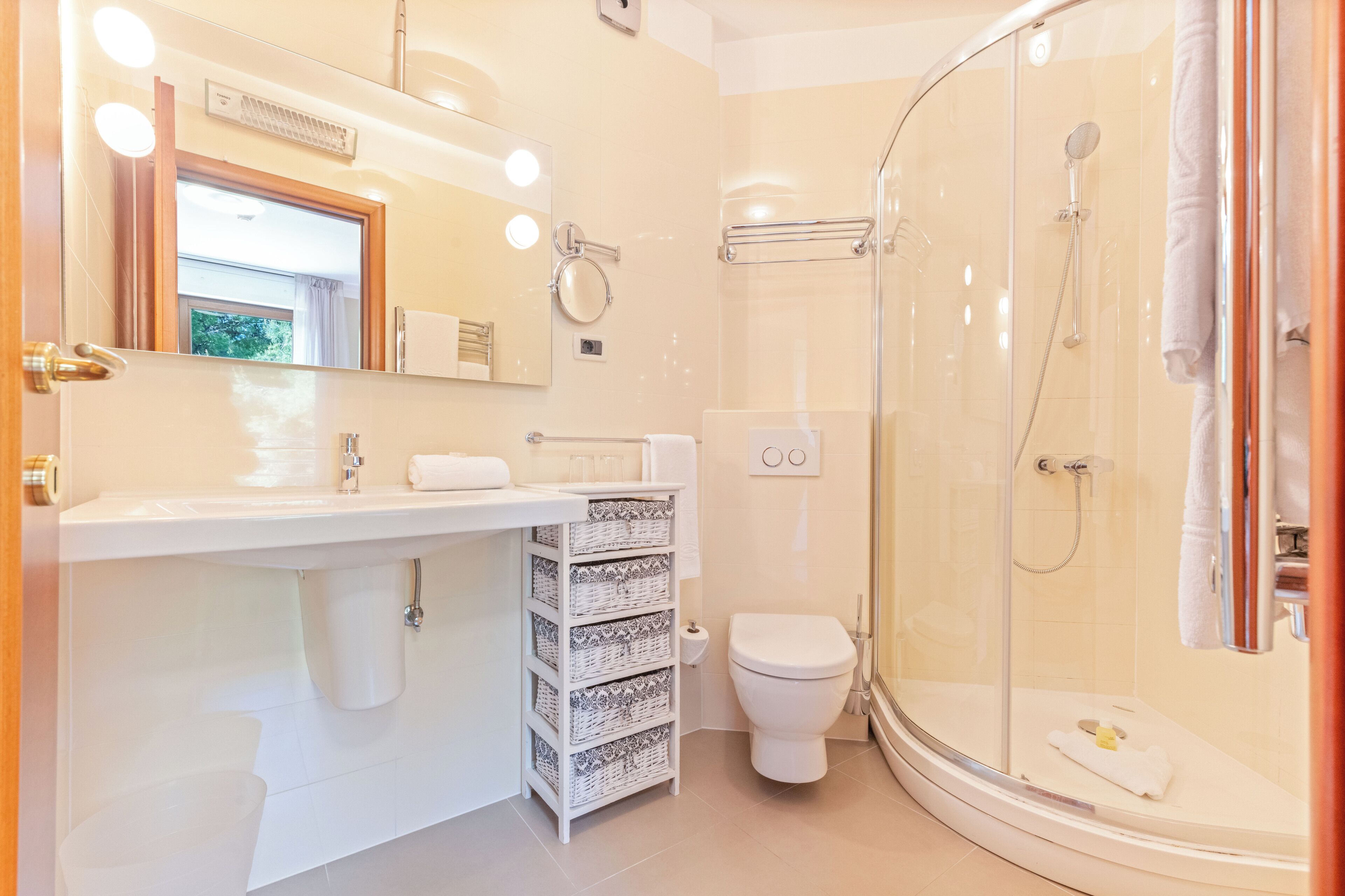 Un bagno moderno con doccia vetro, lavandino bianco con specchio e servizi igienici.