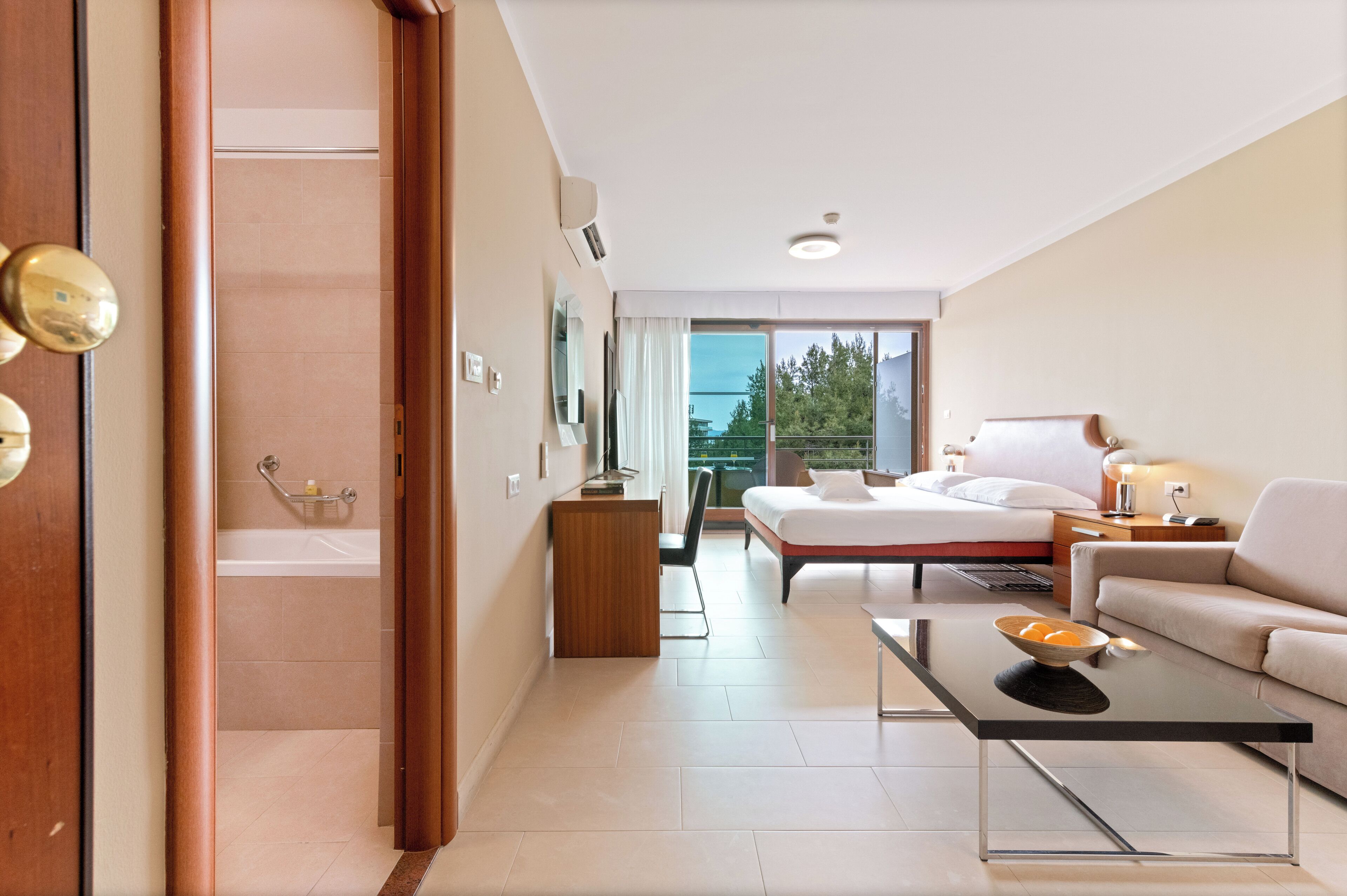 Una habitación de hotel moderna con cama, sofá y un escritorio pequeño.