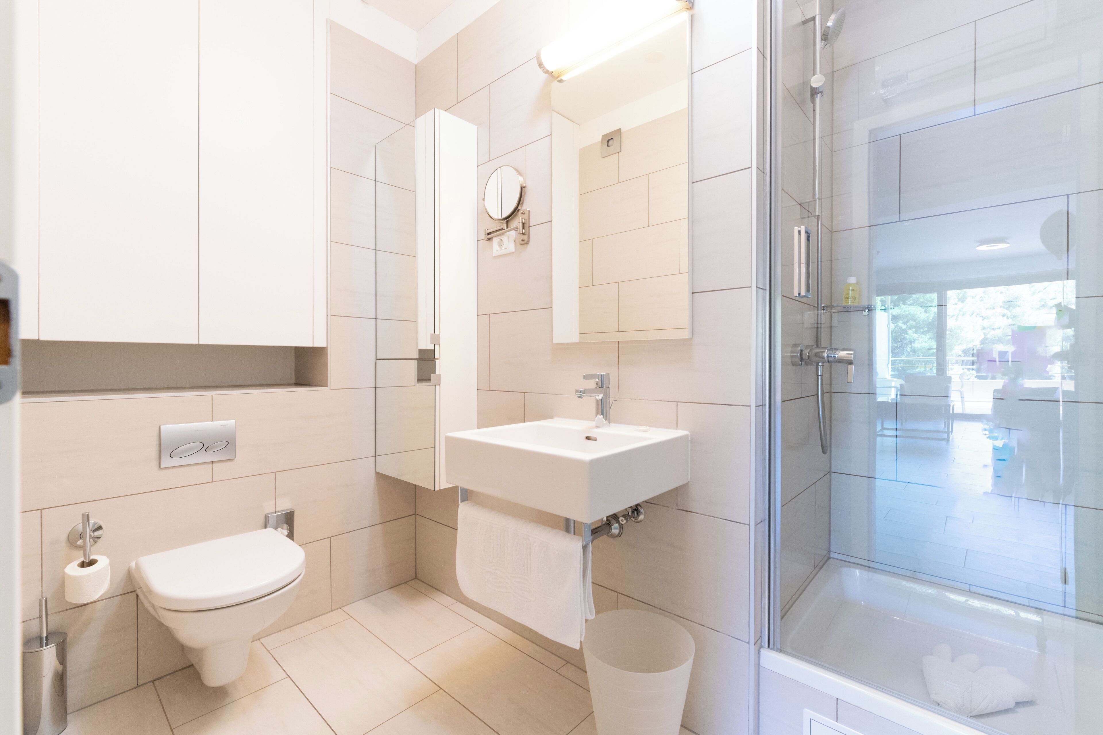 Ein modernes Badezimmer mit Toilette, Waschbecken, Spiegel und einer Duschkabine.