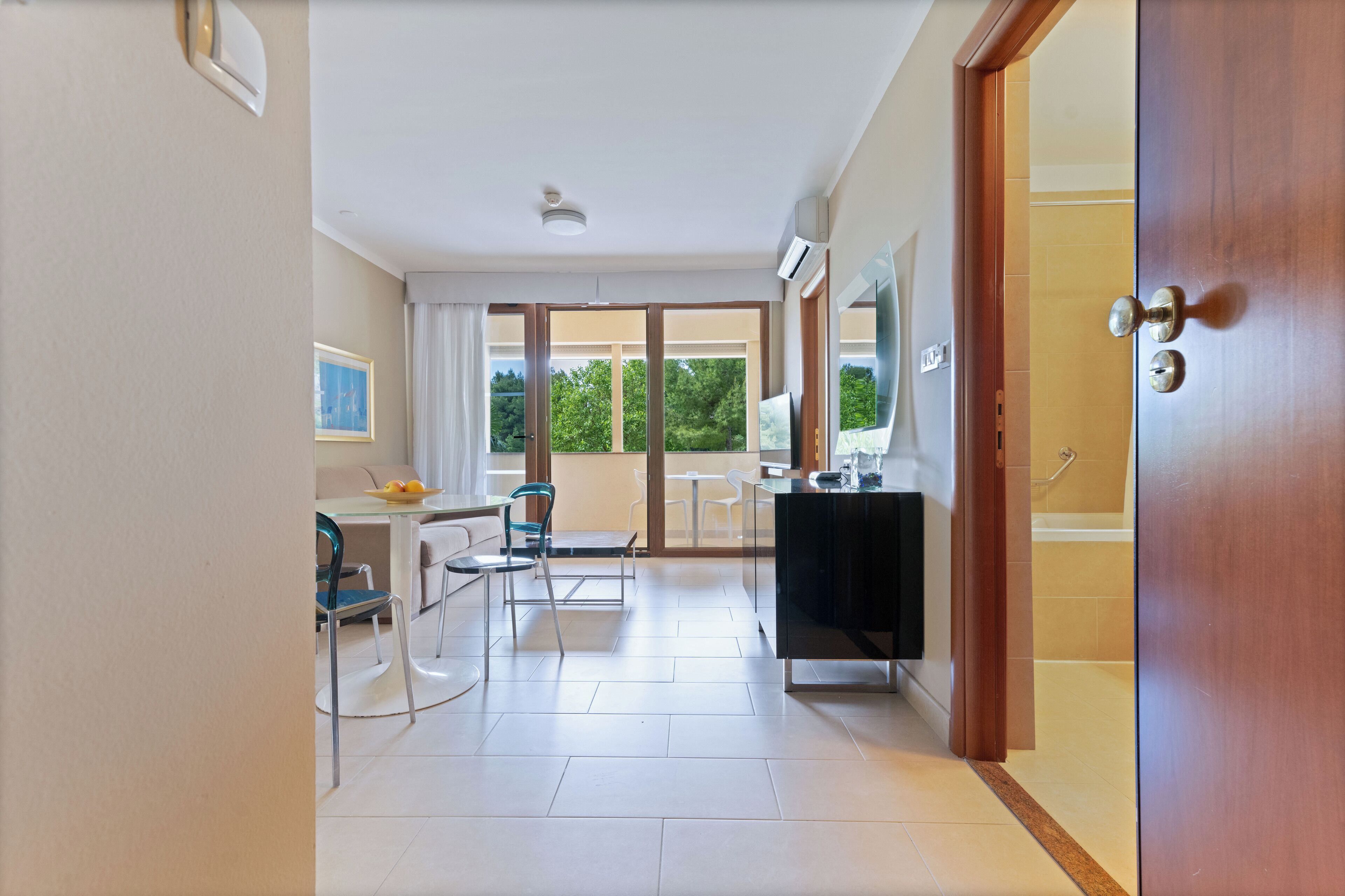 A modern room with a dining area, a black cabinet, and a sliding glass door leading to a balcony.