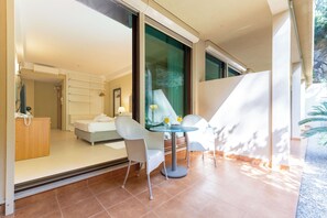 A modern hotel room with a balcony, a dining area with a table and chairs, and a large window offering a view of the outdoors. - The Residence (Podstrana)
