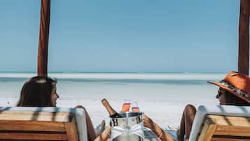 Een privéstrand, ligstoelen aan het strand, parasols, strandlakens