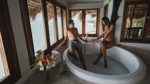 A bathtub with a view of the beach, a vase of flowers, and a wooden ceiling. - Las Nubes de Holbox (Isla Holbox)
