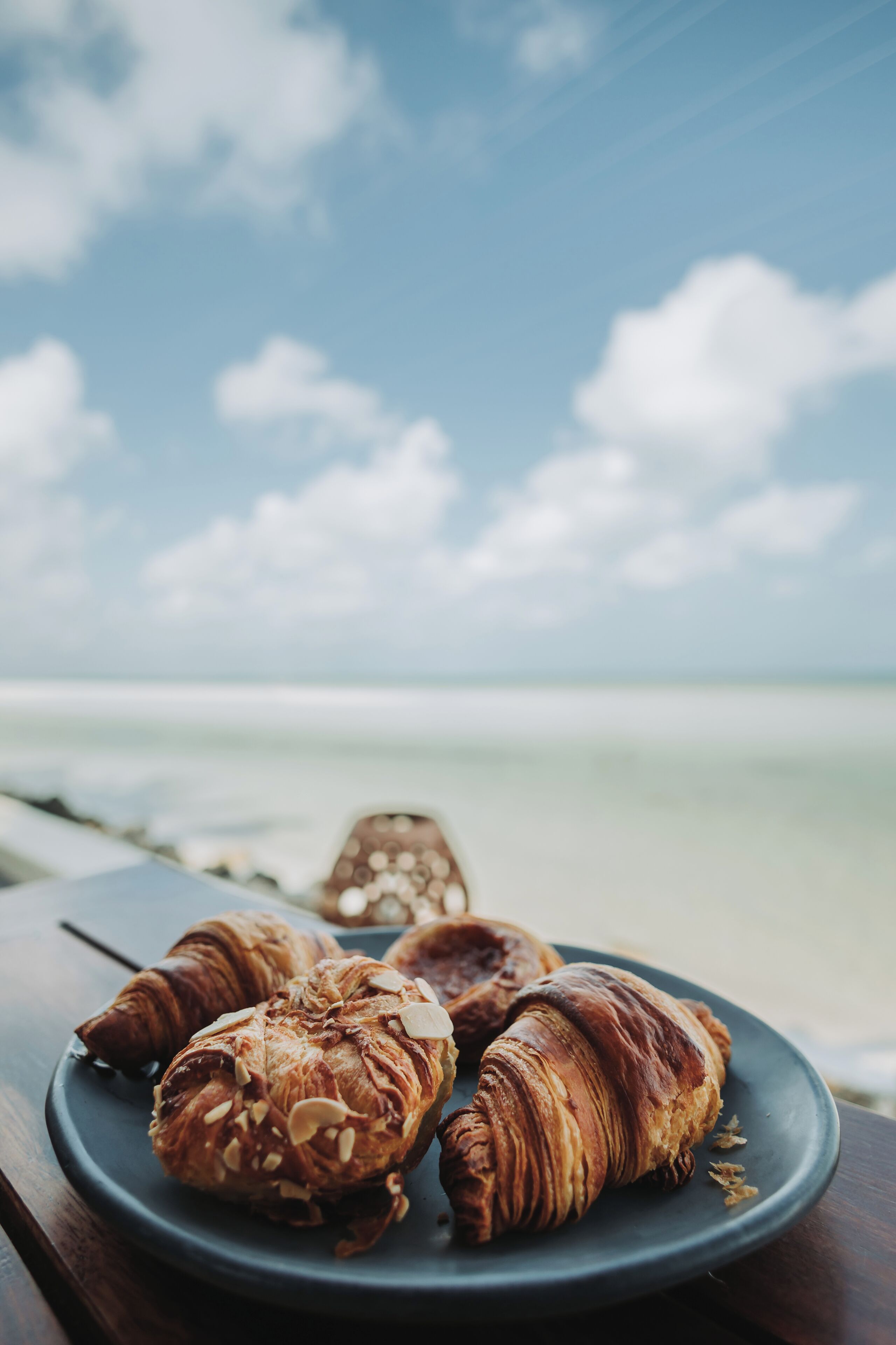 En tallrik med croissanter står på ett bord med utsikt över havet och himlen i bakgrunden.