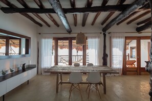Un comedor con una mesa y sillas de madera, una lámpara colgante y vistas al balcón.