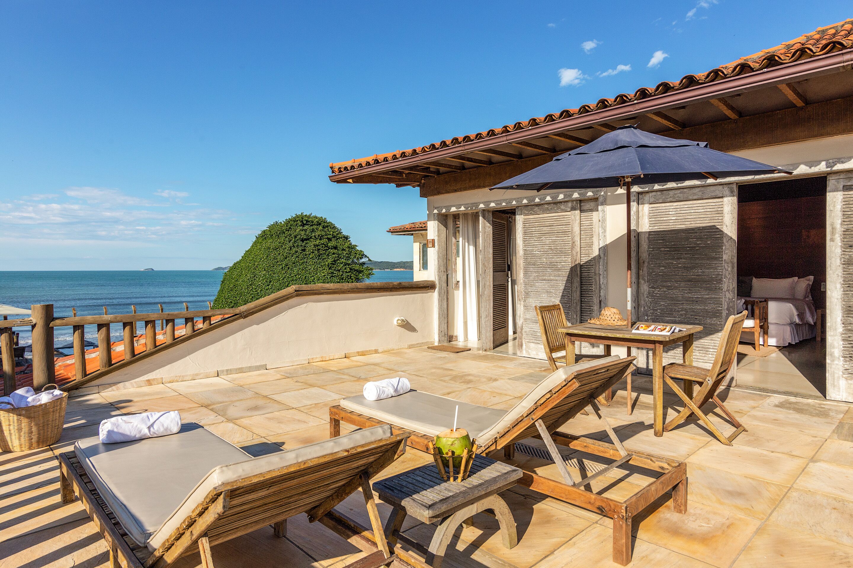 Une terrasse avec des fauteuils, une table et une vue sur la mer.