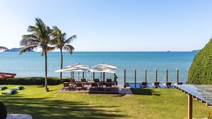A deck with outdoor seating, palm trees, and a view of the sea. - Villa Rasa (Búzios)