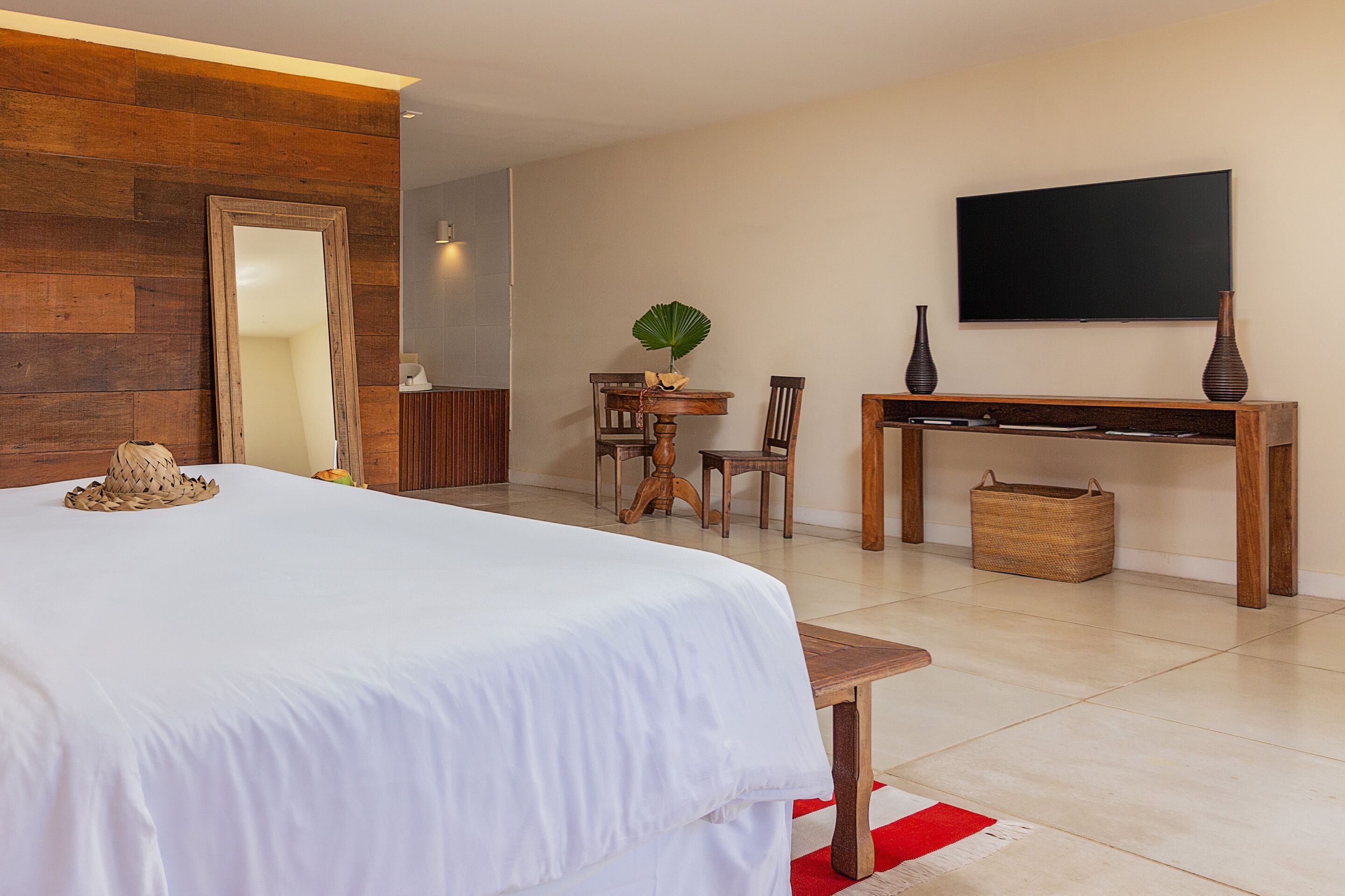 A hotel room with a large bed, a wooden desk, a television, and a mirror.