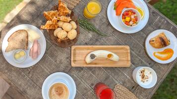 A breakfast spread on a wooden table with various food items and drinks.