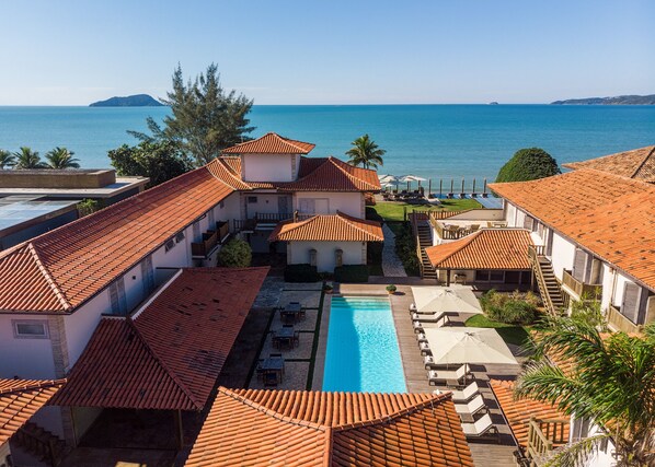 A resort with a swimming pool, outdoor seating, and a view of the sea. - Villa Rasa (Búzios)
