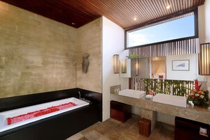 Casa de banho moderna com uma banheira preta, um espelho grande e uma toucador com lavatório.