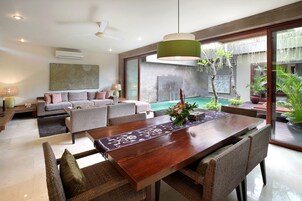 Sala de estar moderna com área de jantar, ventilador de teto e vista para uma piscina.