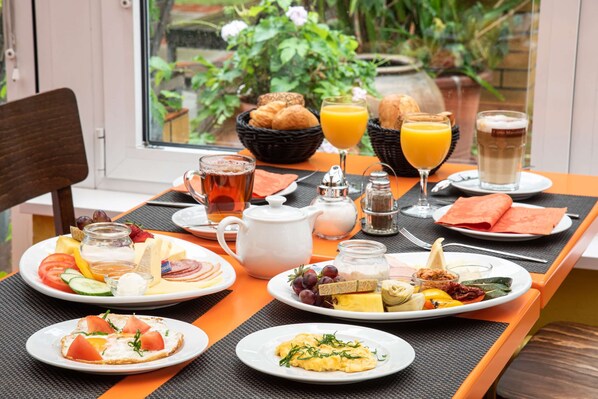 A breakfast table with various dishes, including toast, eggs, and fruit, along with beverages and condiments. - Hotel Grenzfall Berlin (Berlin)