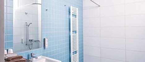 A bathroom with a white sink, a mirror, a towel rack, and a shower area.