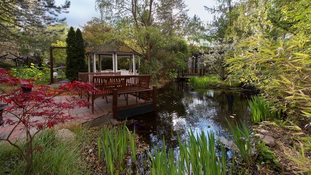 A serene garden with a gazebo, a pond, and lush greenery. - Hotel Grenzfall Berlin (Berlin)