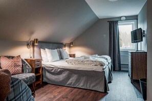 A bedroom with a bed, bedside tables, a TV, a window, and a view of the outdoors. - Trillevallen Högfjällshotell (Undersaker)