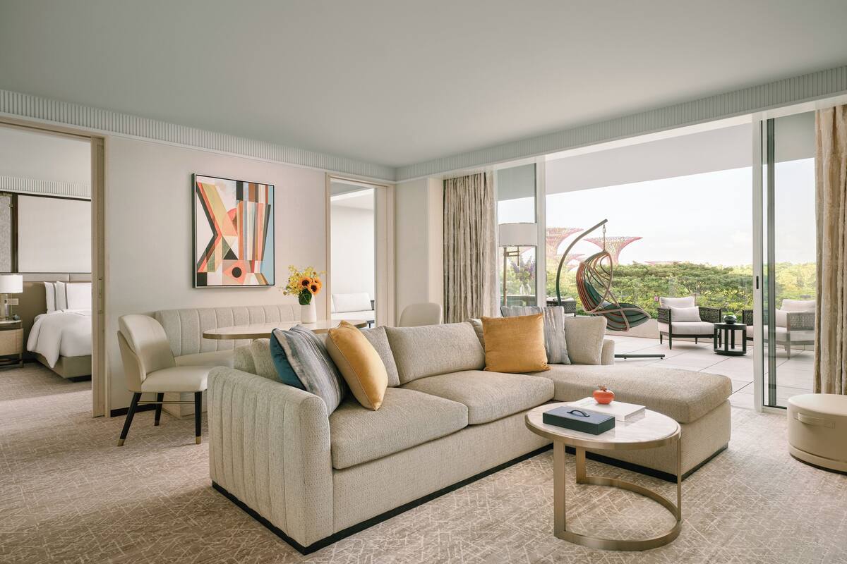 A modern living room with a beige sofa, a round coffee table, and a large window offering a view of the outdoors.
