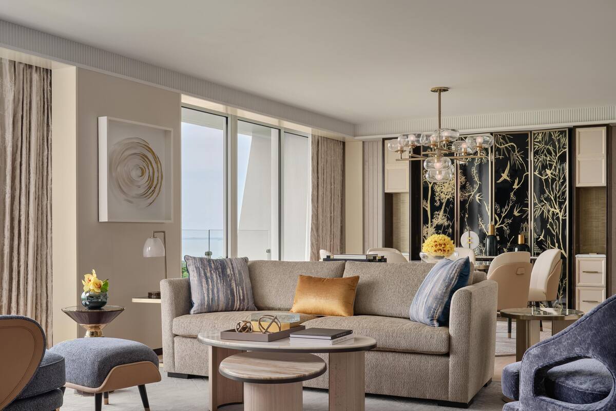 A modern living room with a sofa, armchairs, a coffee table, and a decorative wall panel.