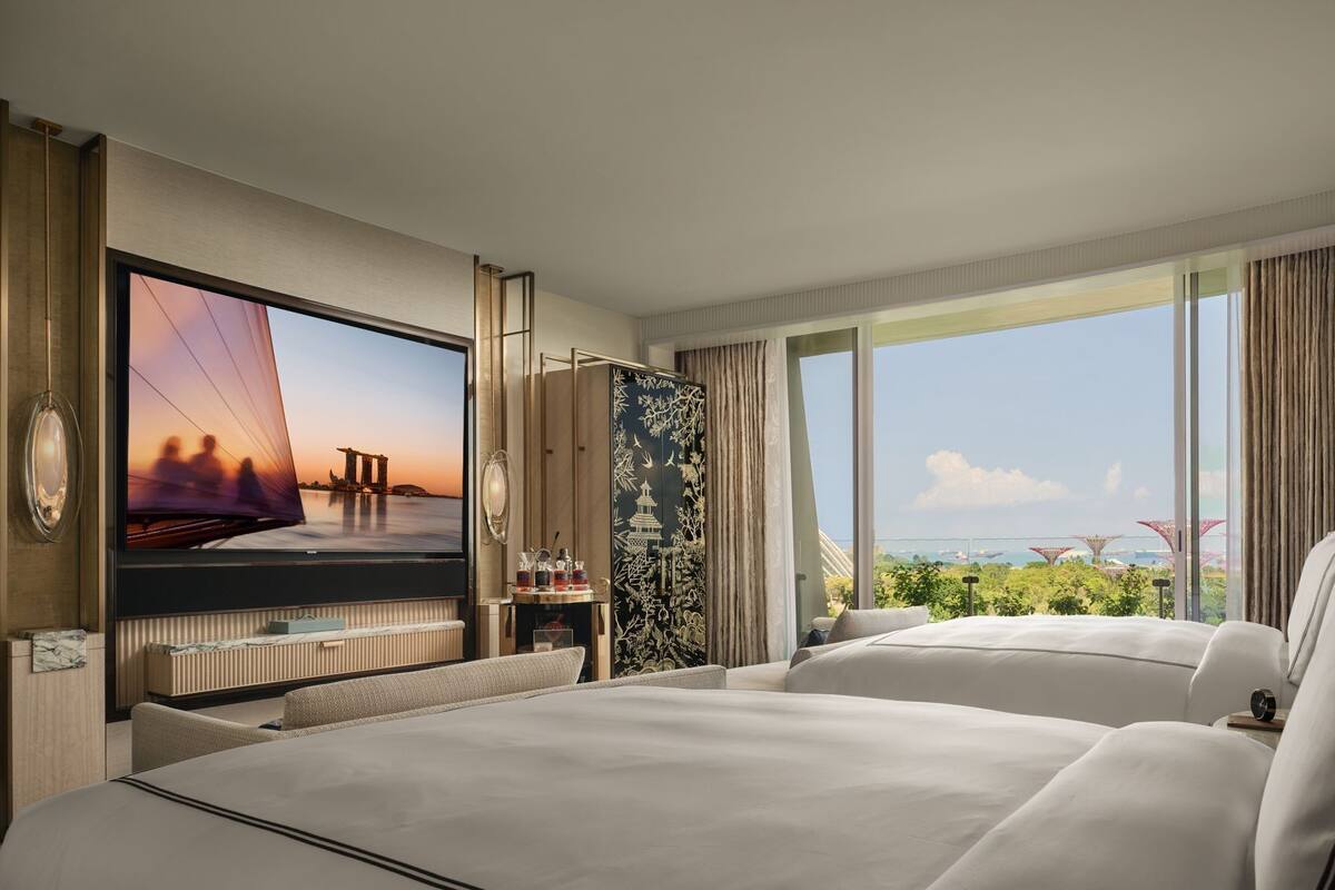 A hotel room with a large bed, a television, and a view of a bridge and greenery.