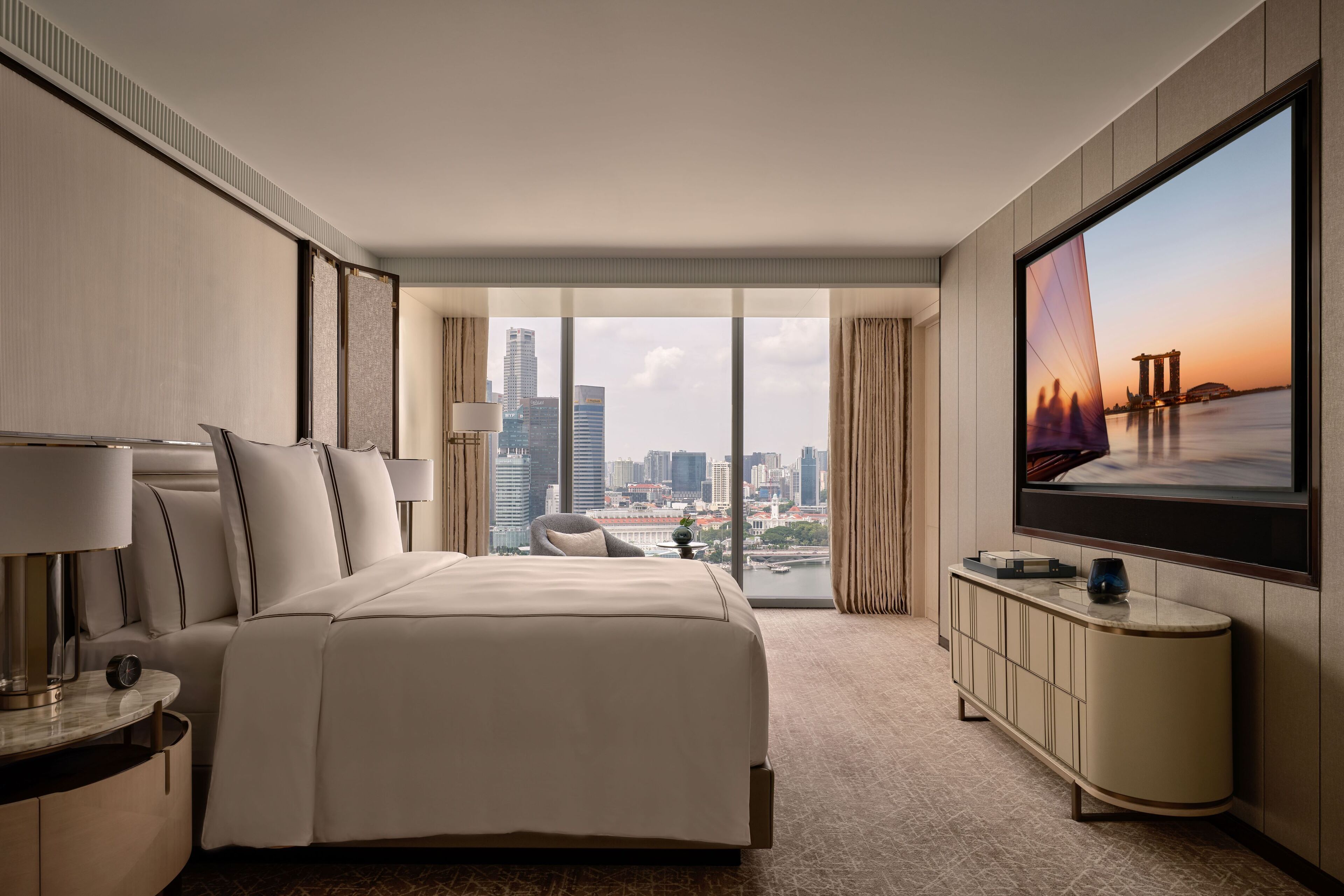 Habitación de hotel moderna con una cama grande, televisión y vistas al horizonte de la ciudad.