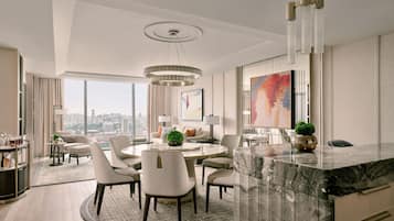 A modern hotel room with a marble dining table, comfortable seating, a city view, and a large abstract painting.