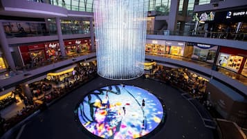 A multi-level shopping mall with a large, illuminated central feature and various retail stores on each level.