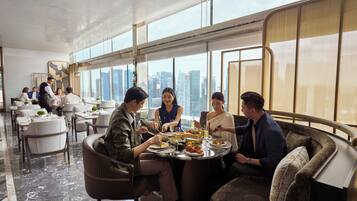 Un comedor moderno con vistas a la ciudad, suelo de mármol y mobiliario contemporáneo.