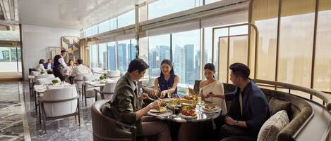 A modern dining area with a city view, marble flooring, and contemporary furniture.