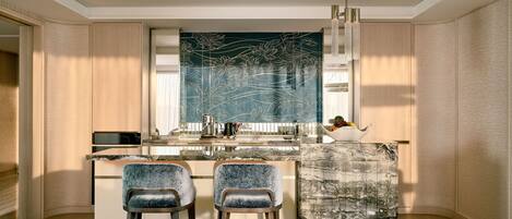 A modern kitchen with a central island, two bar stools, and a decorative wall piece.