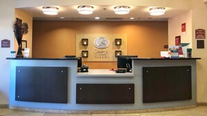 A reception desk with a sign reading "Comfort Suites," a computer, and various informational signs. - Comfort Suites Near City of Industry - Los Angeles (La Puente)