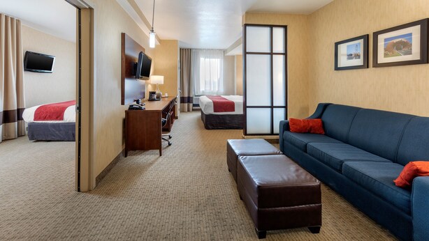 A hotel room with a bed, a desk, a sofa, and a TV. - Comfort Suites Near City of Industry - Los Angeles (La Puente)