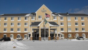 Een groot hotel met een centrale ingang, meerdere verdiepingen en een met sneeuw bedekte grond.