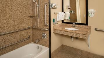A bathroom with a bathtub, a sink, a mirror, and a shower with grab bars.