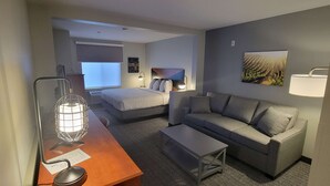 Et hotelværelse med en seng, en sofa, et skrivebord med lampe og et billede på væggen.